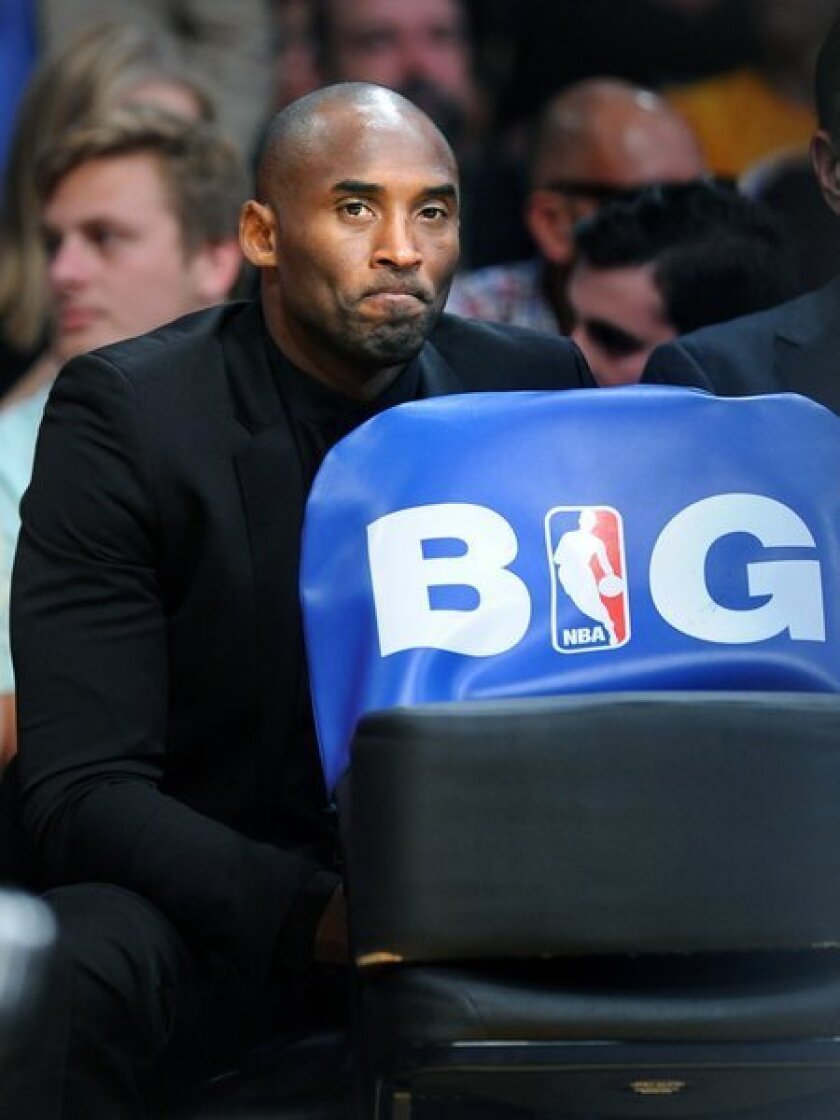 Kobe Bryant sits behind the Lakers' bench during the team's season opener against the Clippers at Staples Center on Tuesday.