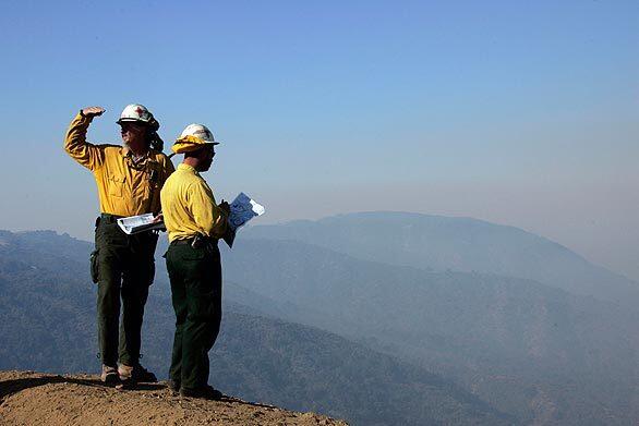 Workers from Gila Hotshots in New Mexico survey the fire area before sending a crew down a steep hill at Newman Point to cut fire line.