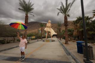 A person holds an umbrella in front of the "Forever Marilyn" statue, designed by US artist John Seward Johnson II, framed by storm clouds as Hurricane Hilary heads north toward southern California, in Palm Springs, California, on August 19, 2023. Hilary brought heavy rains on August 19 to portions of Mexico's Baja California peninsula and the southwestern United States, as officials warned the powerful hurricane was likely to cause "catastrophic and life-threatening" flooding. (Photo by DAVID SWANSON / AFP) / RESTRICTED TO EDITORIAL USE - MANDATORY MENTION OF THE ARTIST UPON PUBLICATION - TO ILLUSTRATE THE EVENT AS SPECIFIED IN THE CAPTION (Photo by DAVID SWANSON/AFP via Getty Images)