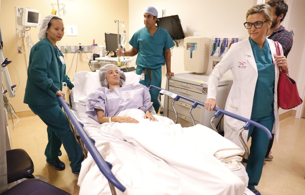Alejandra Campoverdi heads to surgery with Dr. Kristi Funk, right, and Dr. Ritu Chopra, center. (Christina House / Los Angeles Times)