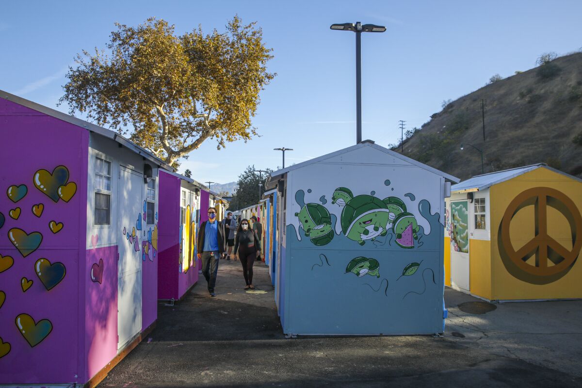 People walks next to tiny homes painted in different colors