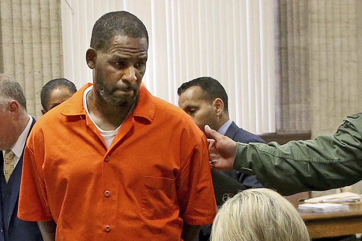 An inmate in an orange jumpsuit looks down.