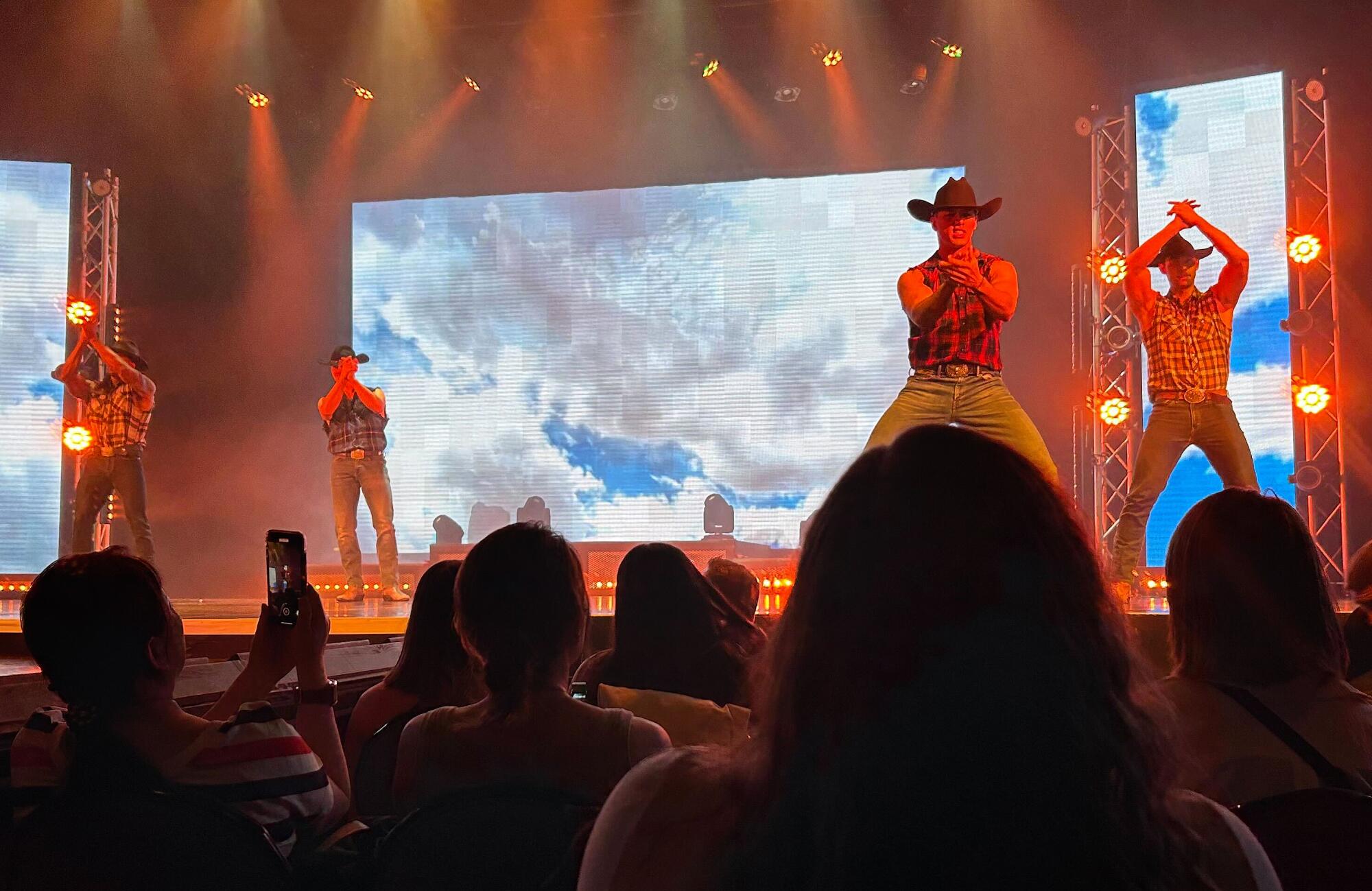 Male dancers in western wear on stage.