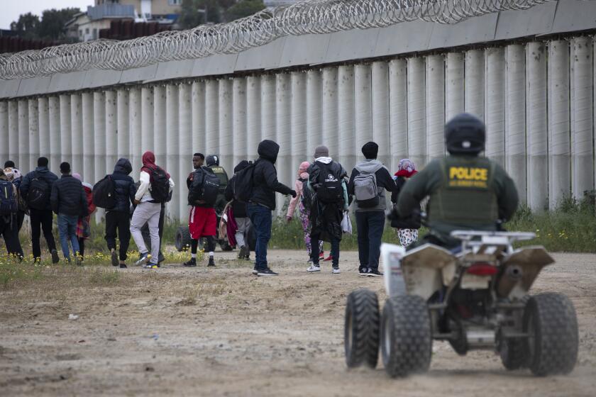 San Diego , California - April 12: Dozens of asylum seeking migrants run out of an open gate before being stopped by U.S. Border Patrol agents on Wednesday, April 12, 2023 in San Diego , California. More than a hundred people from various countries had been apprehended by Border Patrol and said some had been stuck in-between the U.S.-Mexico border walls for as long as seven days. They said that agents gave them no food and minimal water while they were held in custody there. (Ana Ramirez / The San Diego Union-Tribune)