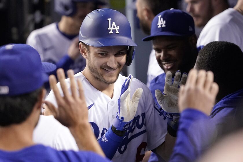 Los Angeles Dodgers' Trea Turner is congratulated by teammates in the dugout.