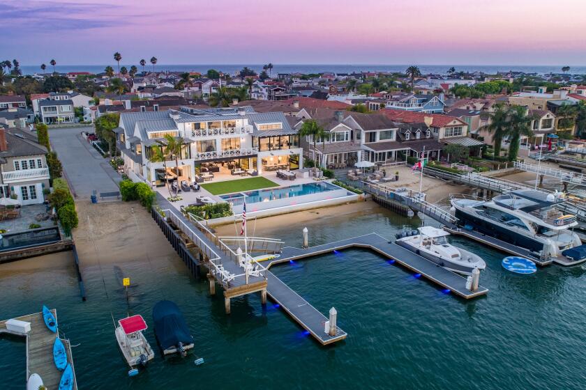 The nearly 13,000-square-foot harbor-facing house at 1813 E. Bay Ave. in Newport Beach features a five-car garage, an outdoor fire pit, an infinity pool, a glass elevator, two kitchens, a theater, a sauna, a private beach and a dock with frontage for eight small boats.