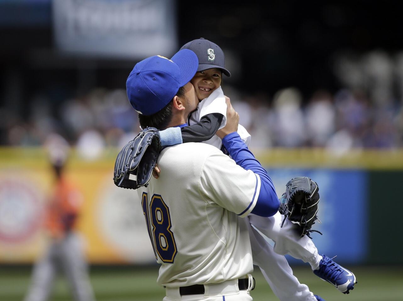 Seattle Mariners' Hisashi Iwakuma gives a kiss to his son Towa after the child was among several players' children throwing out the ceremonial first pitch on Father's Day before a baseball game against the Houston Astros, Sunday, June 21, 2015, in Seattle. (AP Photo/Elaine Thompson)