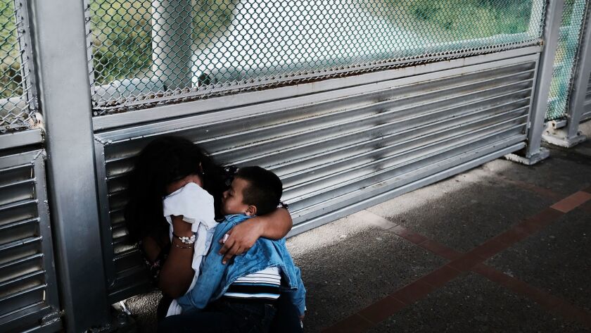 A crying Honduran woman and her child wait on the border bridge after being denied entry into the U.S. in Brownsville, Texas, on June 22.
