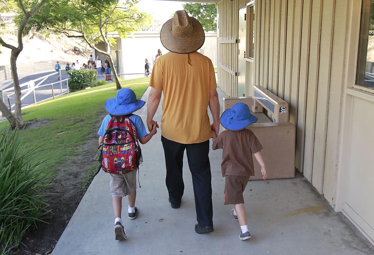 Two students and their dad head for the classroom on the first day of school at Top of the World Elementary in 2014. A project at the school will replace three portable buildings with permanent structures and add a music facility.