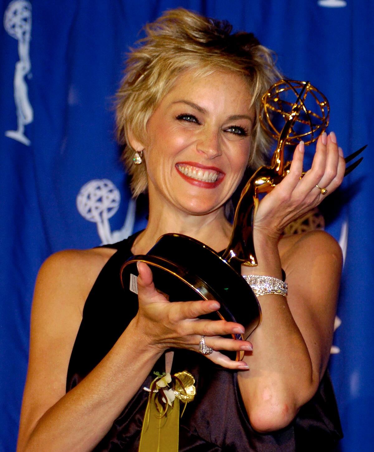 Actress Sharon Stone smiles broadly as she holds up an Emmy statuette