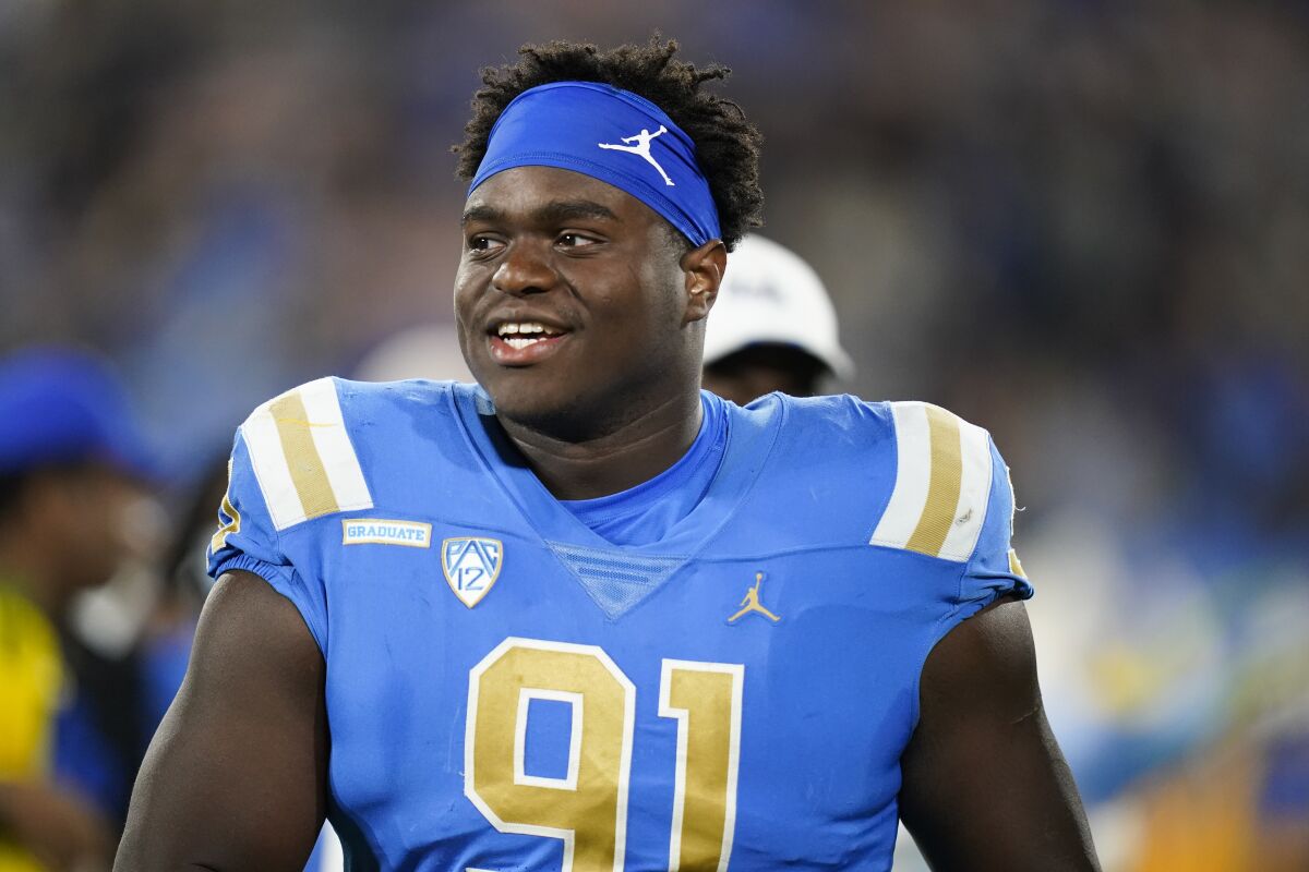 UCLA defensive lineman Otito Ogbonnia smiles as he walks on the field.