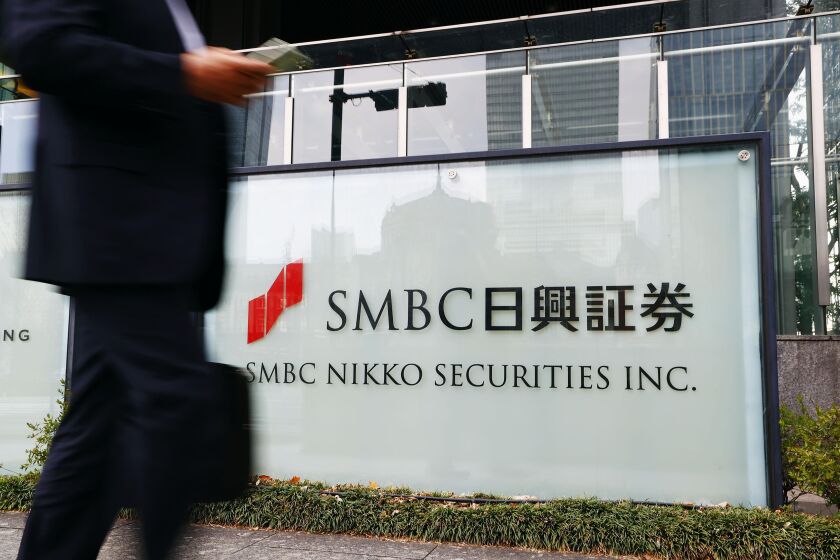 FILE - A person walks past a signboard of SMBC Nikko Securities in Tokyo on March 24, 2022. Japan’s Financial Services Agency on Friday, Oct. 7, 2022 ordered brokerage SMBC Nikko Securities to suspend its block trading operations for three months as part of penalties in a market manipulation case. (Kyodo News via AP, File)
