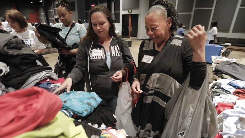 Jeniese Reppe, left, and Nina Schauf pick out clothes at Project Homeless Connect East County event held at the Rock Church in El Cajon.