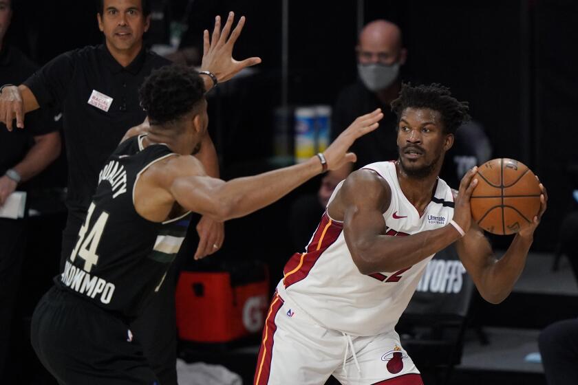 Miami Heat's Jimmy Butler (22), right, looks to pass around Milwaukee Bucks' Giannis Antetokounmpo (34) during the first half of an NBA conference semifinal playoff basketball game Wednesday, Sept. 2, 2020, in Lake Buena Vista, Fla. (AP Photo/Mark J. Terrill)