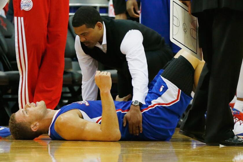 Clippers forward Blake Griffin is attended to by team trainer Jasen Powell after suffering a back spasm during the first half of Saturday's game against the Houston Rockets.