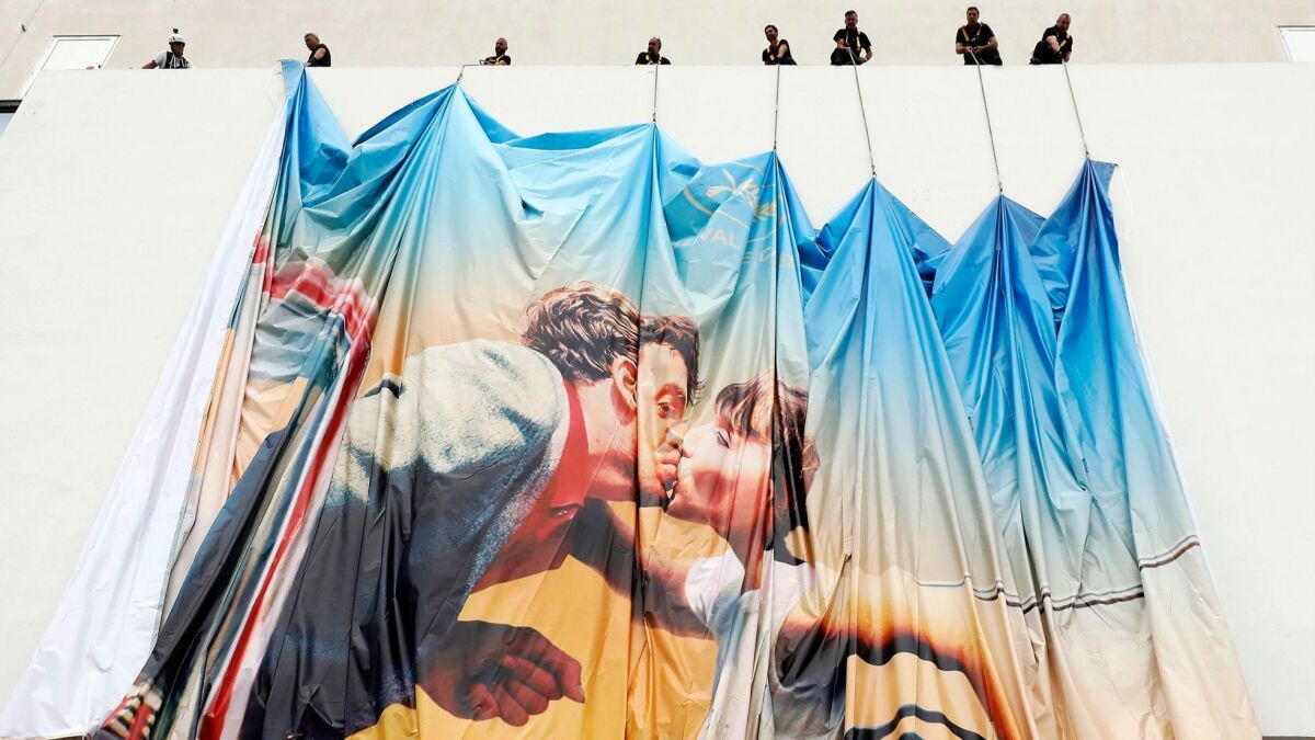 Workers install the official poster of the 71st Cannes Film Festival on the Palais des Festivals facade in Cannes, France.