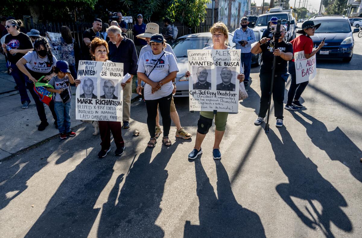 Residents hold posters with photographs of two of the LAPD officers involved in the fireworks explosion on 27th Street.