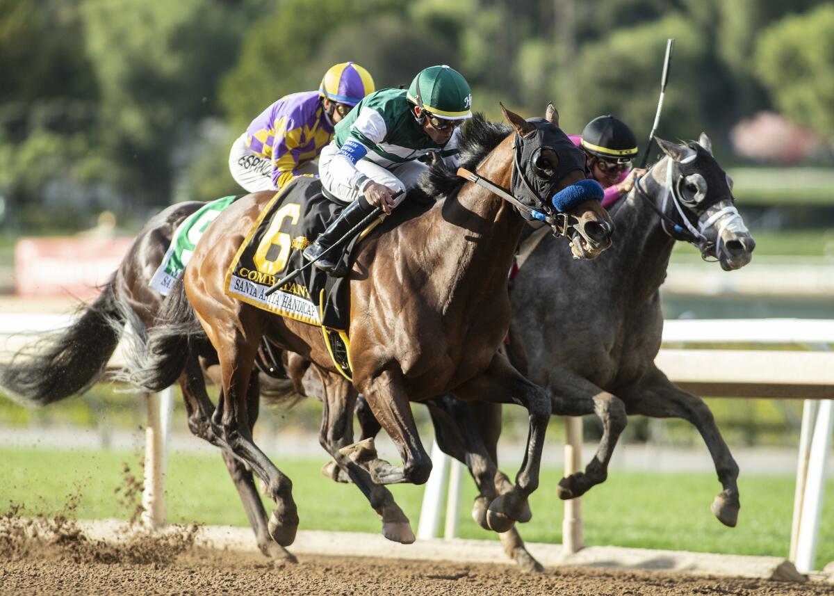 Jockey Joel Rosario guides Combatant on the outside for a win over Multiplier, right, with Tyler Gaffalione aboard, to win the Grade I, $600,000 Santa Anita Handicap on Saturday. Midcourt and jockey Victor Espinoza trail the leaders.