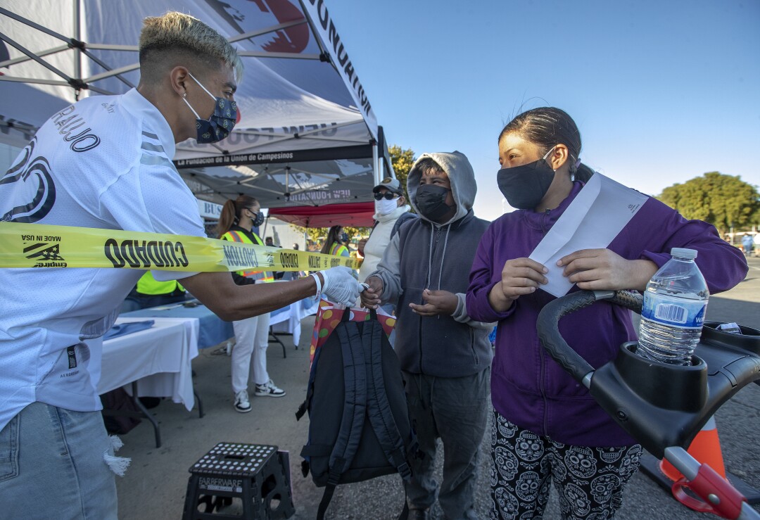 Los Angeles Galaxy soccer player Julian Araujo hands out a backpack filled with food.