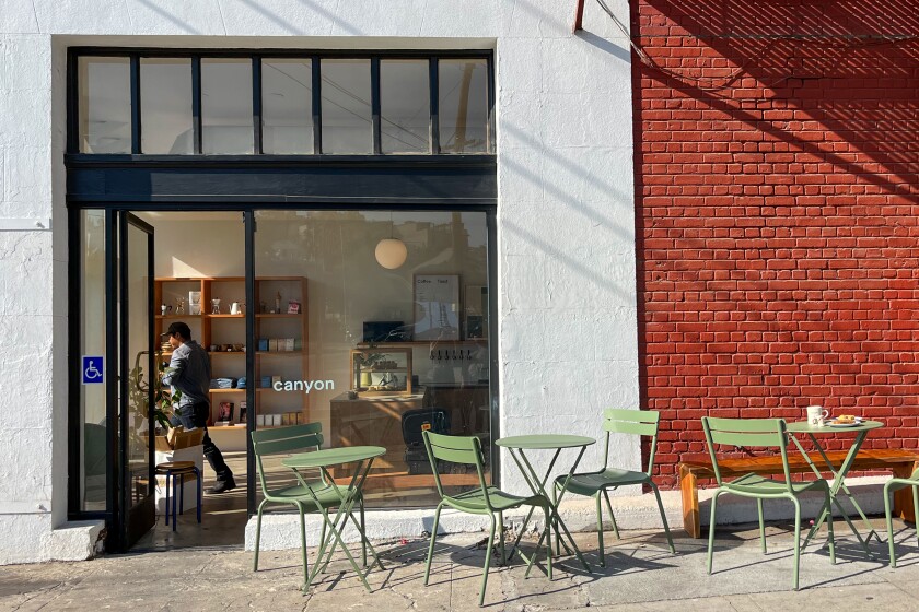 A photo of Canyon Coffee's exterior, including patio seating against a red brick wall.