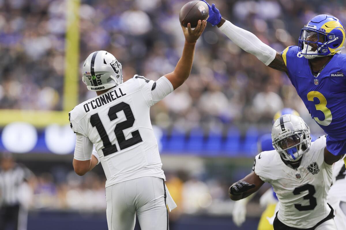 Raiders quarterback Aidan O'Connell attempts to throw a pass as Rams safety Kam Curl jumps to block it.