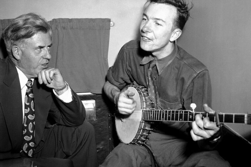 Peter Seeger, right, performs in 1948 for former Vice President Henry A. Wallace on a plane between Norfolk and Richmond, Va. Seeger died at 94.