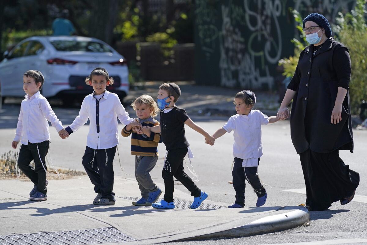 Una mujer y un grupo de niños pequeños cruzan una calle del barrio de Midwood, en Brooklyn, Nueva York,