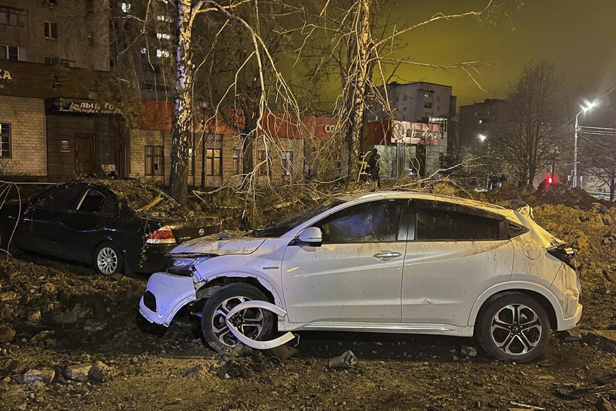 Damaged cars amid a bombed city landscape at night