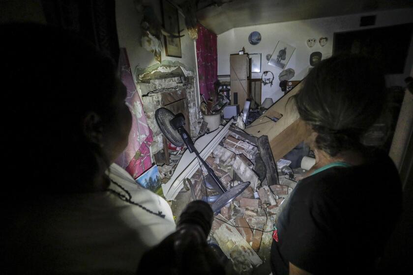 Chavela Padilla, left, an emergency response team member, walks with Trona resident Ronnie Calvert as she sorts through the rubble of her home.