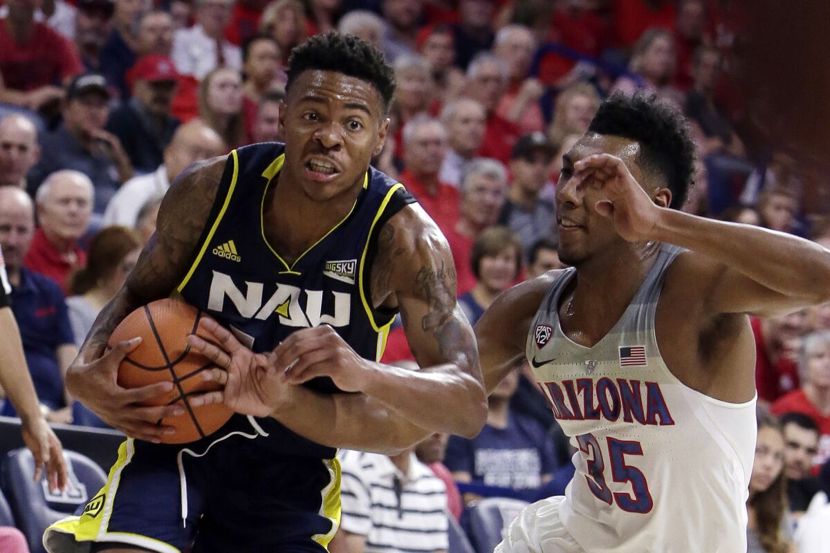 FILE - In this Nov. 10, 2017, file photo, Northern Arizona guard Karl Harris drives on Arizona guard Allonzo Trier (35) during the first half during an NCAA college basketball game in Tucson, Ariz. Another dream, of playing in the NCAA Tournament, became a reality when Northern Kentucky clinched the Horizon League tournament title in March. Mere hours later, it was snatched away by a pandemic spiderwebbing across the globe. (AP Photo/Rick Scuteri, FIle)