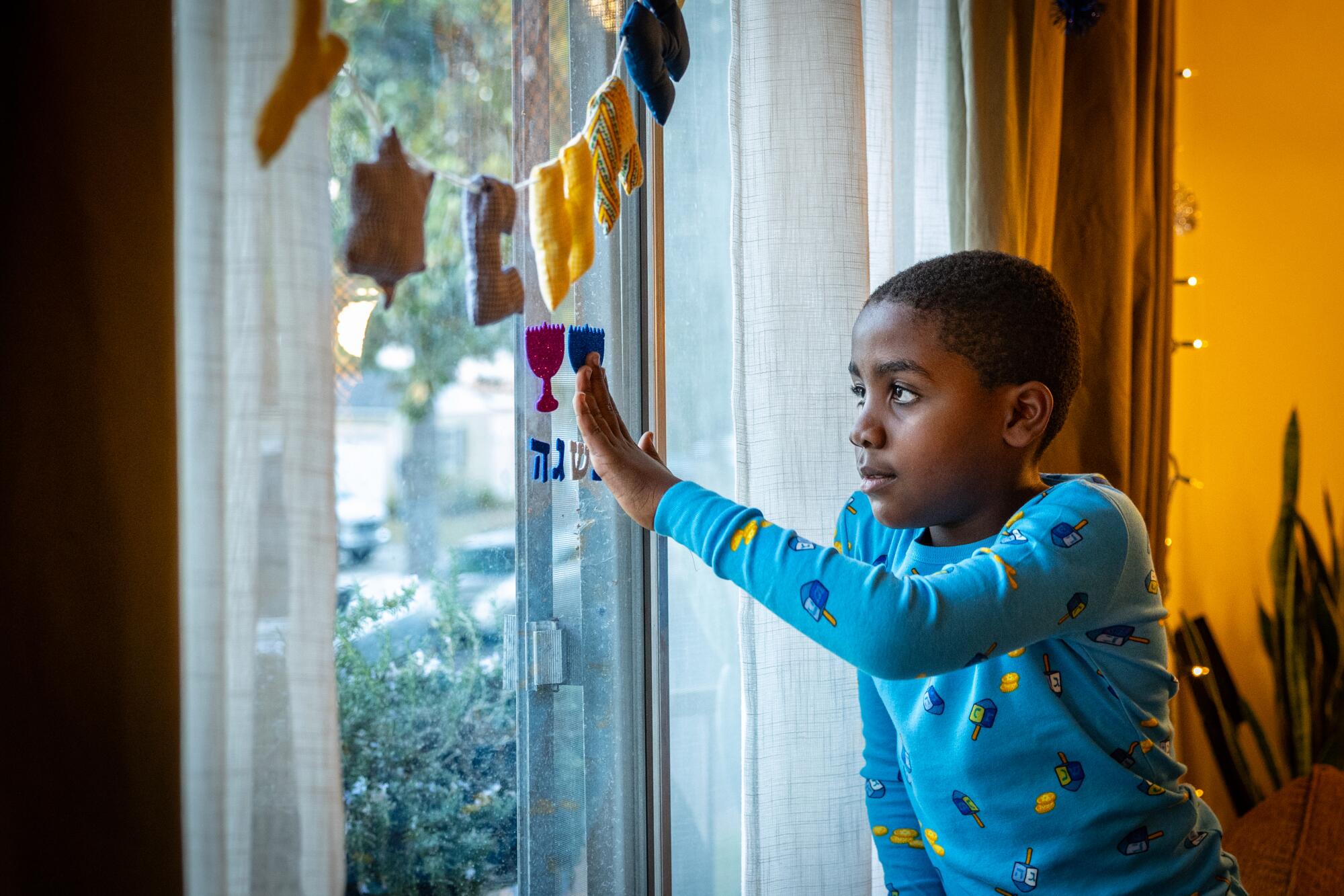 A boy places decorations in a window.