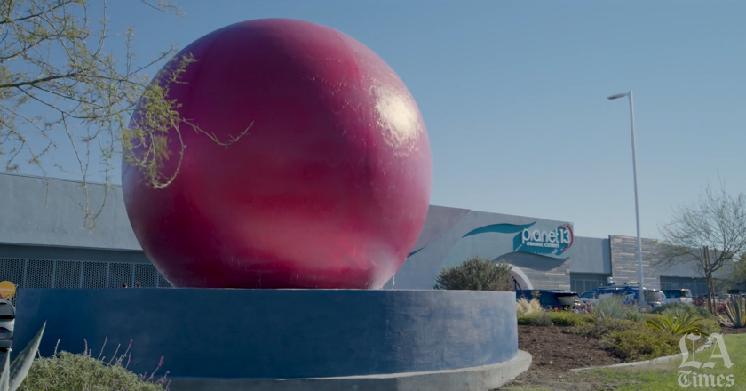  A large red globe that's also a water element with a building in the background.