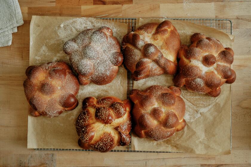 LONG BEACH, CA - SEPTEMBER 30: Gusto Bread Owner Arturo Enciso brushes melted butter onto freshly baked pan de muerto and coats them in a variet of toppings -- granulated sugar, powdered sugar, or prior to baking with an egg wash and sesame seeds -- at Gusto Bread on September 30, 2024 in Long Beach, CA. (Shelby Moore / For The Times)