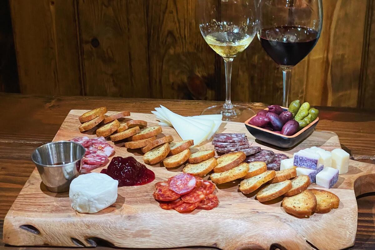 A charcuterie and cheese board, a glass of red wine and a glass of white wine behind.