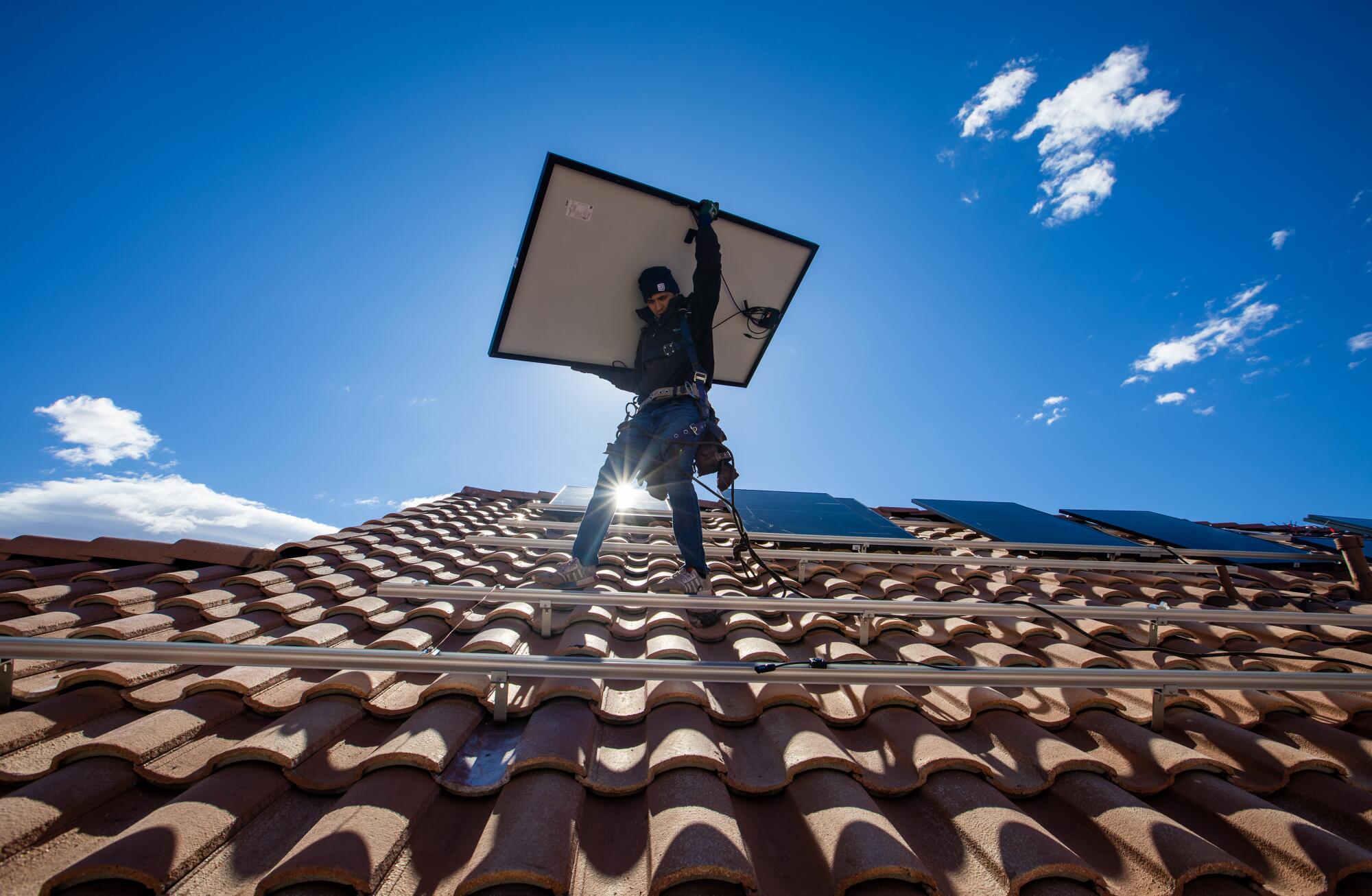 A Sunrun employee installs solar panels on a roof in North Las Vegas.