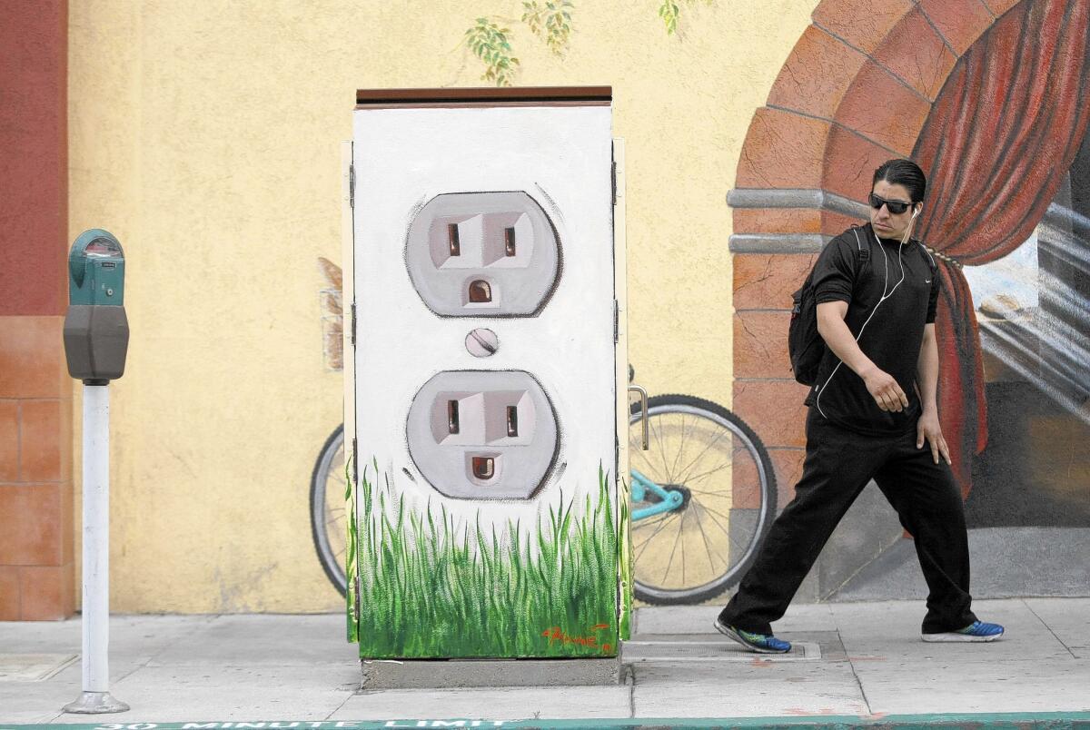 A man takes a long look at a utility box mural painted with electrical outlets at California Avenue and Brand Boulevard in Glendale on Wednesday, May 21, 2014. T