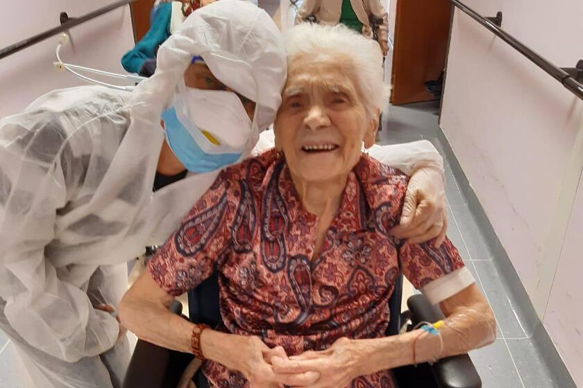In this photo taken on April 1, 2020, 103-year-old Ada Zanusso, poses with a nurse at the old people's home "Maria Grazia" in Lessona, northern Italy, after recovering from Covid-19 infection. To recover from coronavirus infection, as she did, Zanusso recommends courage and faith, the same qualities that have served her well in her nearly 104 years on Earth. The new coronavirus causes mild or moderate symptoms for most people, but for some, especially older adults and people with existing health problems, it can cause more severe illness or death. (Residenza Maria Grazia Lessona via AP Photo)