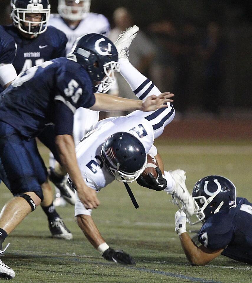 Newport Harbor High's Chance Siemonsma is tripped up by Trabuco Hills defensive back Bret Bohan, lower right, on Friday.