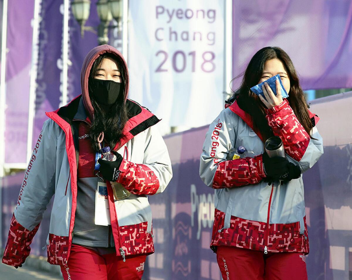 Olympic volunteers walk outside the main press center in Pyeongchang.