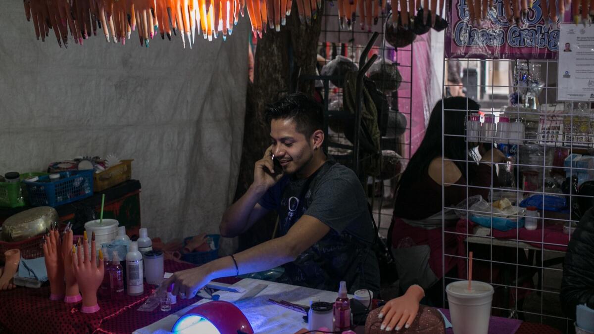 Habib Mansur, 22, sits at the stall where he works as a nail artist in one of Mexico City's beauty markets.