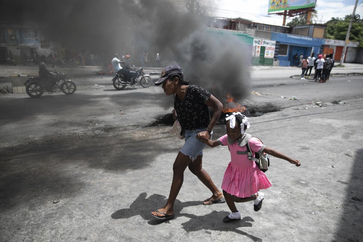 A woman and child walk past a fire on a street.