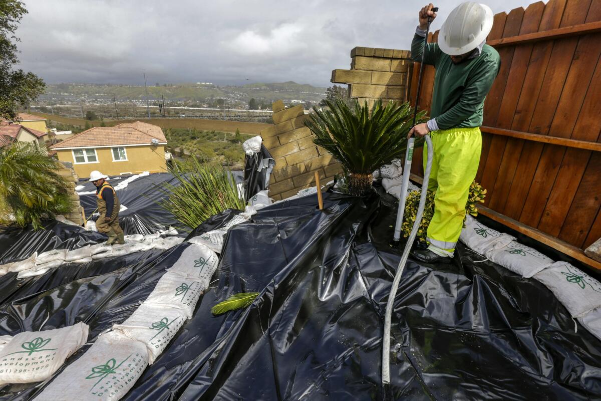 Gonsalo Garcia, right, pumps accumulated rainwater to prevent further erosion on a sliding hillside in Canyon Country on March 2.