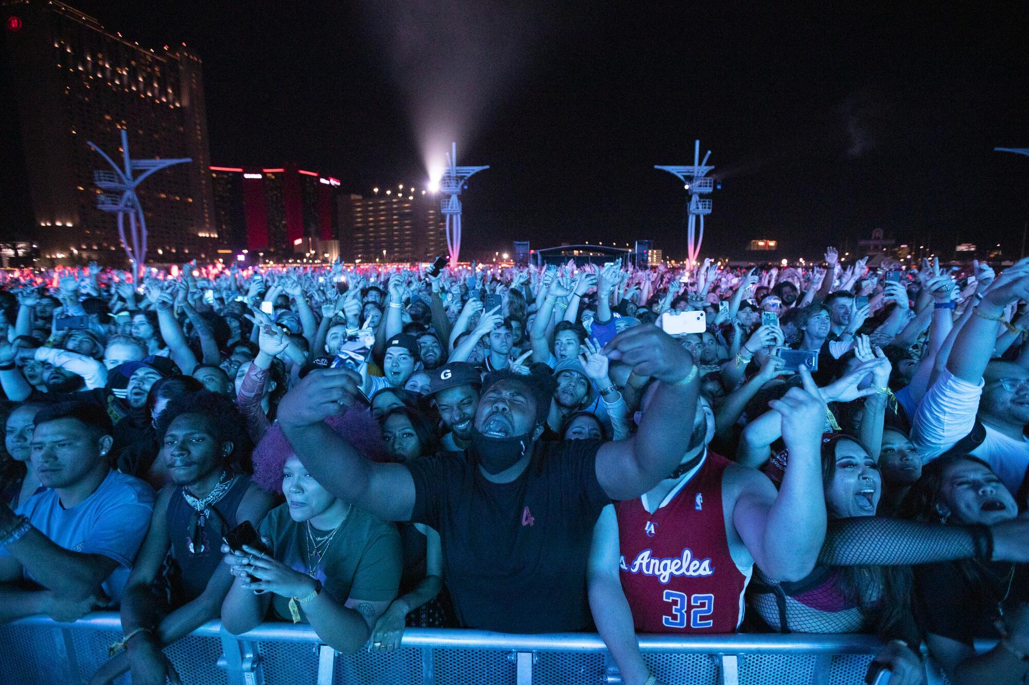 Fans with arms raised stand behind a barrier.