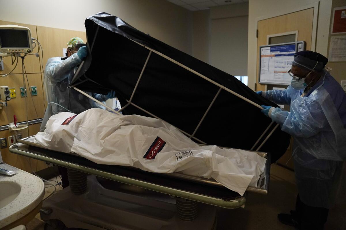 Workers prepare to move the body of a COVID-19 victim to the hospital's morgue.