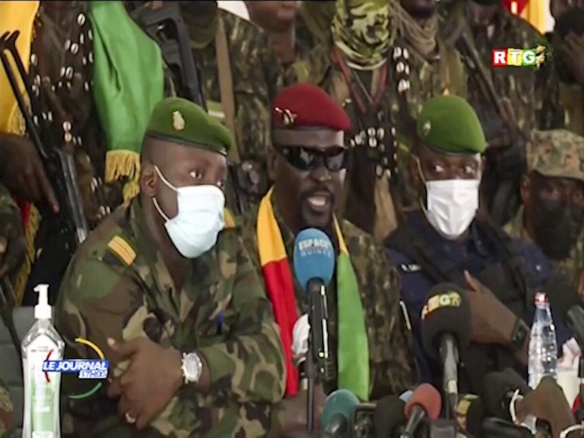 In this image made from video, Junta leader Col. Mamady Doumbouya, center, wearing a red beret and sunglasses, addresses officials in the capital Conakry, Guinea Monday, Sept. 6, 2021. Guinea's new military leaders sought to tighten their grip on power Monday after overthrowing President Alpha Conde, ordering the soldiers from his presidential guard to now join the junta forces and barring government officials from leaving the country. (Radio Television Guineenne via AP)