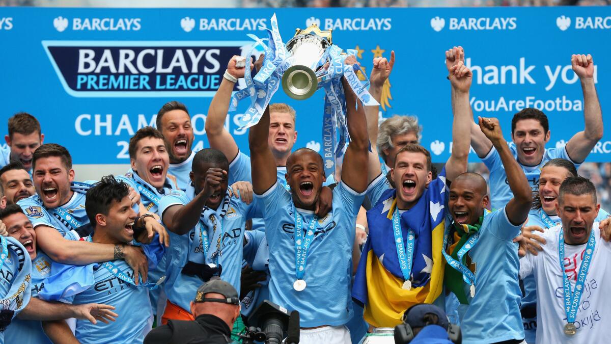 Vincent Kompany of Manchester City lifts the Premier League trophy following the team's championship victory over West Ham United in Manchester, England, on May 11.