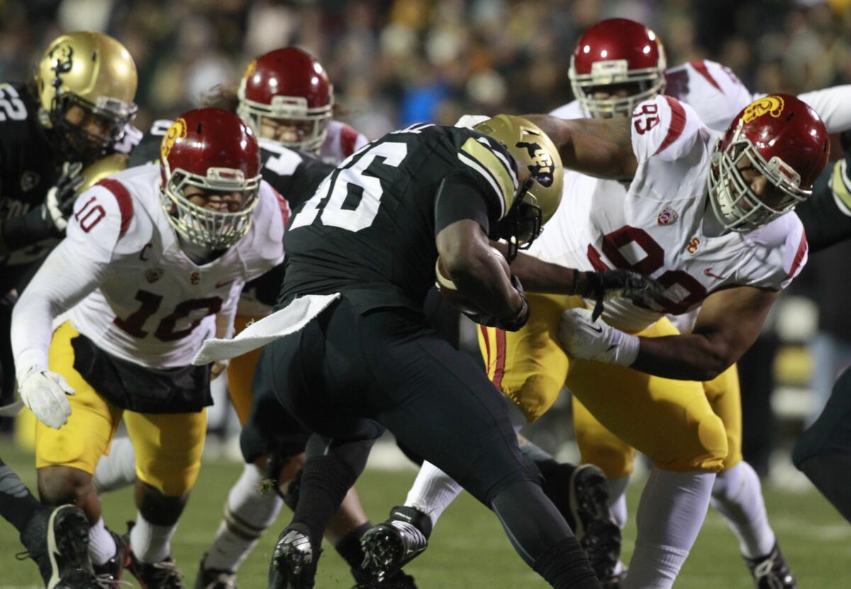 USC's Antwaun Woods helps tackle Colorado tailback Christian Powell for a loss last November.
