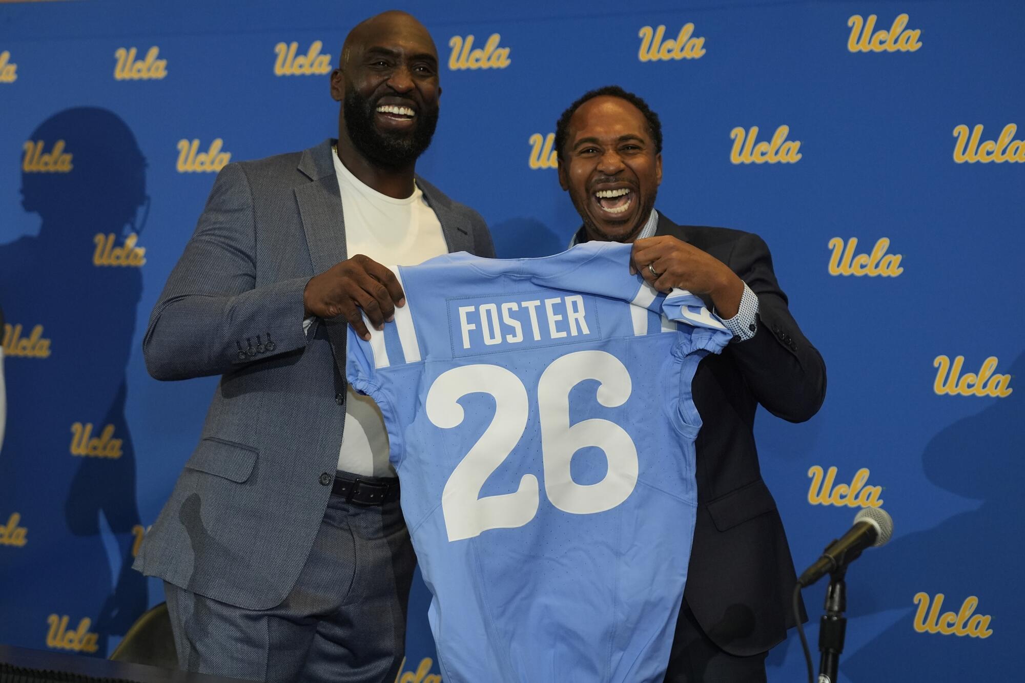 DeShaun Foster and Martin Jarmond  pose with a Bruins jersey.