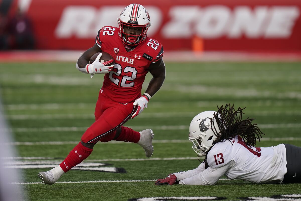 FILE - In this Dec. 19, 2020, file photo, Utah running back Ty Jordan (22) runs for a score as he eludes a tackle by Washington State linebacker Jahad Woods (13) during the second half of an NCAA college football game in Salt Lake City. This was supposed to be Jordan’s time. Instead, Utah approaches a new football season facing the unexpected and unwanted challenge of replacing Jordan in the backfield. Jordan died at 19 after an accidental shooting on Dec. 26. (AP Photo/Rick Bowmer, File)