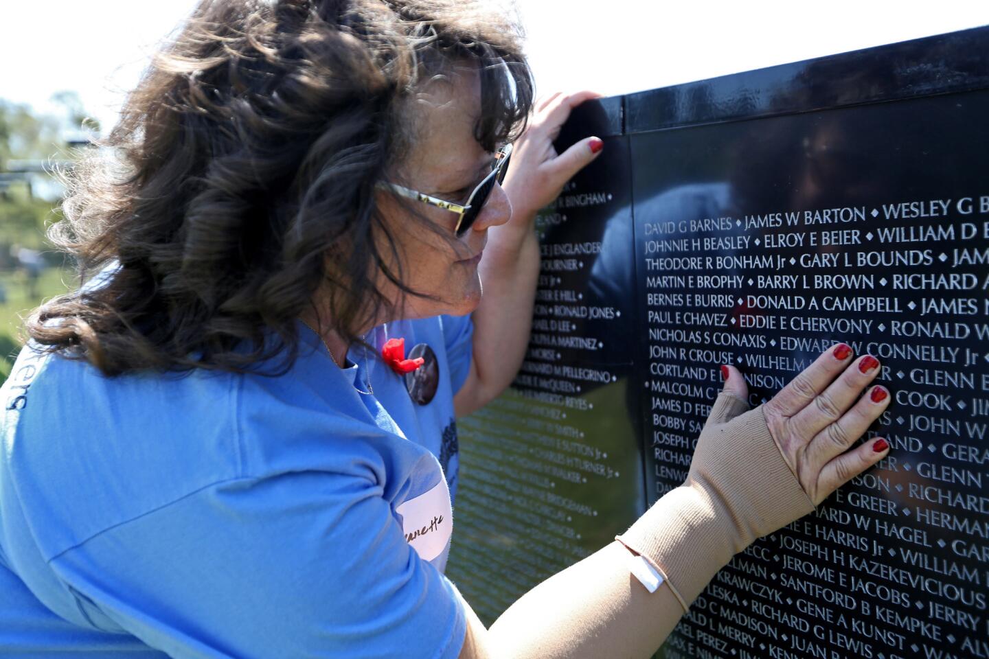 Jeanette Chervony, 52, of Costa Mesa points to her father Eddie Chervony's name on the traveling replica of the Vietnam Veterans Memorial Wall, at Estancia Park in Costa Mesa on Wednesday. Chervony was 13 months old when her father, a member of the U.S. Army 77th Field Artillery, was killed in combat on May 5, 1968 at age 21.